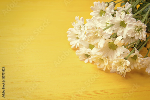 Bouquet of daisy flowers on yellow wooden background