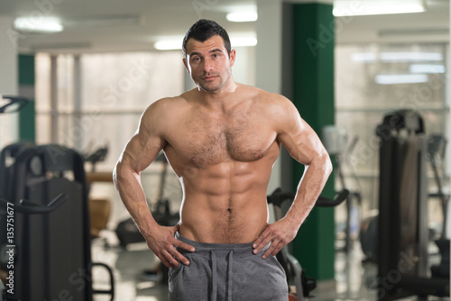Hairy Muscular Man Flexing Muscles In Gym