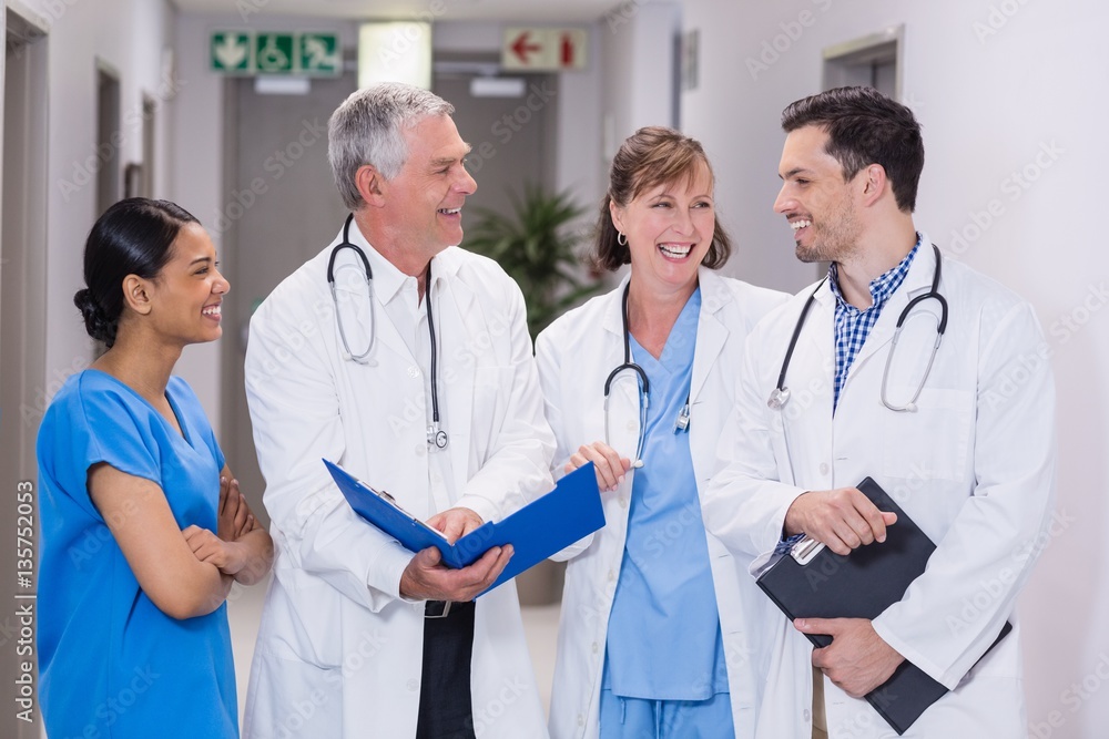 Fototapeta premium Smiling nurse and doctors discussing over clipboard