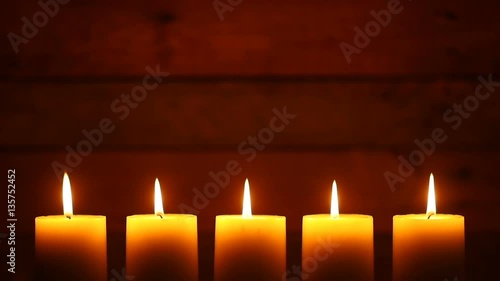 This is a video of five candles with flames at the bottom of the frame leaving lots of space for copy on a blank retro ship wood background