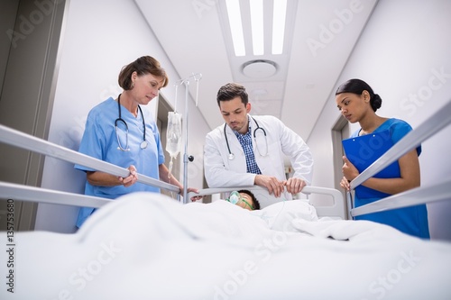 Doctors examining patient in corridor 