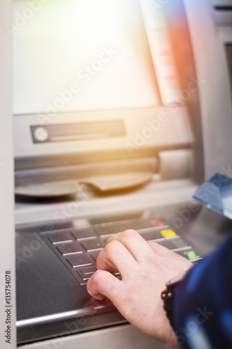 Hand of a man with a credit card, using an ATM. Man using an atm machine with his credit card.