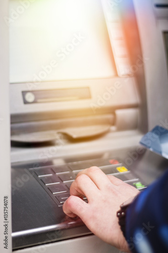 Hand of a man with a credit card  using an ATM. Man using an atm machine with his credit card.