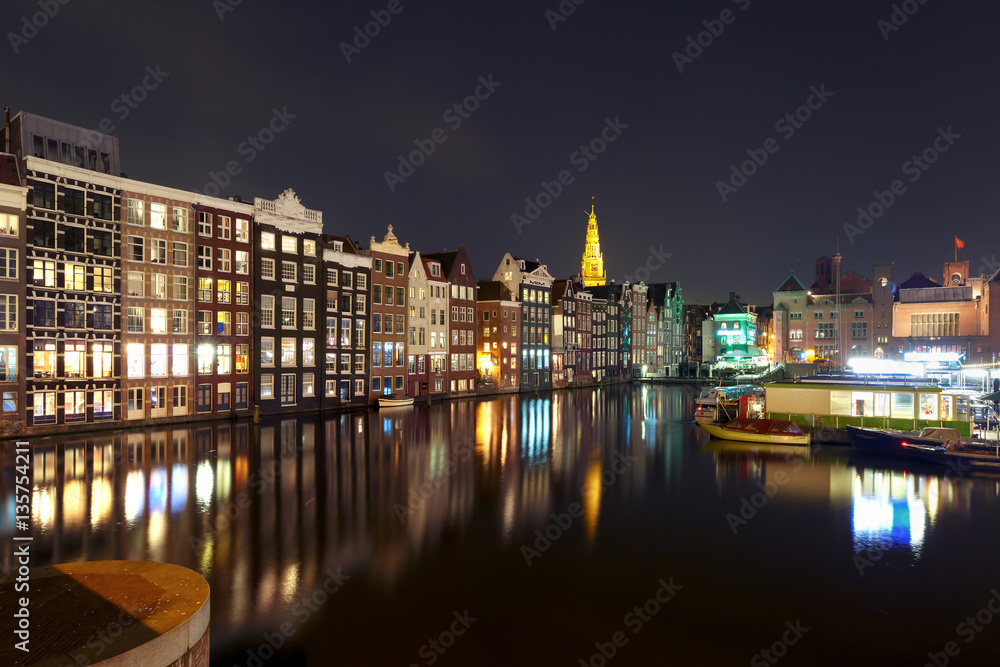 Amsterdam canal with typical houses and Oude Kerk church during twilight blue hour, Holland, Netherlands