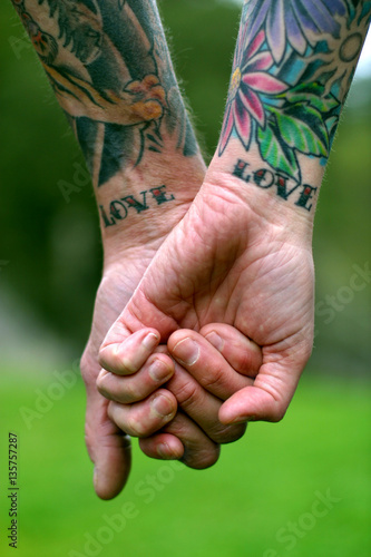 Valokuva A couple holding hands with LOVE tattooed on their wrists