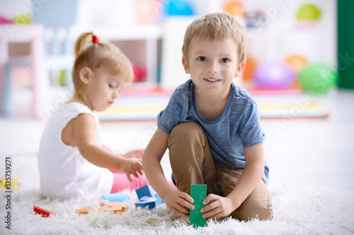 Cute little boy playing with colorful blocks at home