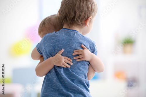 Cute little girl hugging brother at home