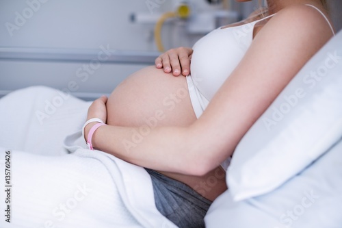 Mid section pregnant woman relaxing on hospital bed