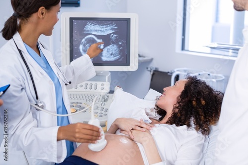 Doctor doing ultrasound scan for pregnant woman photo