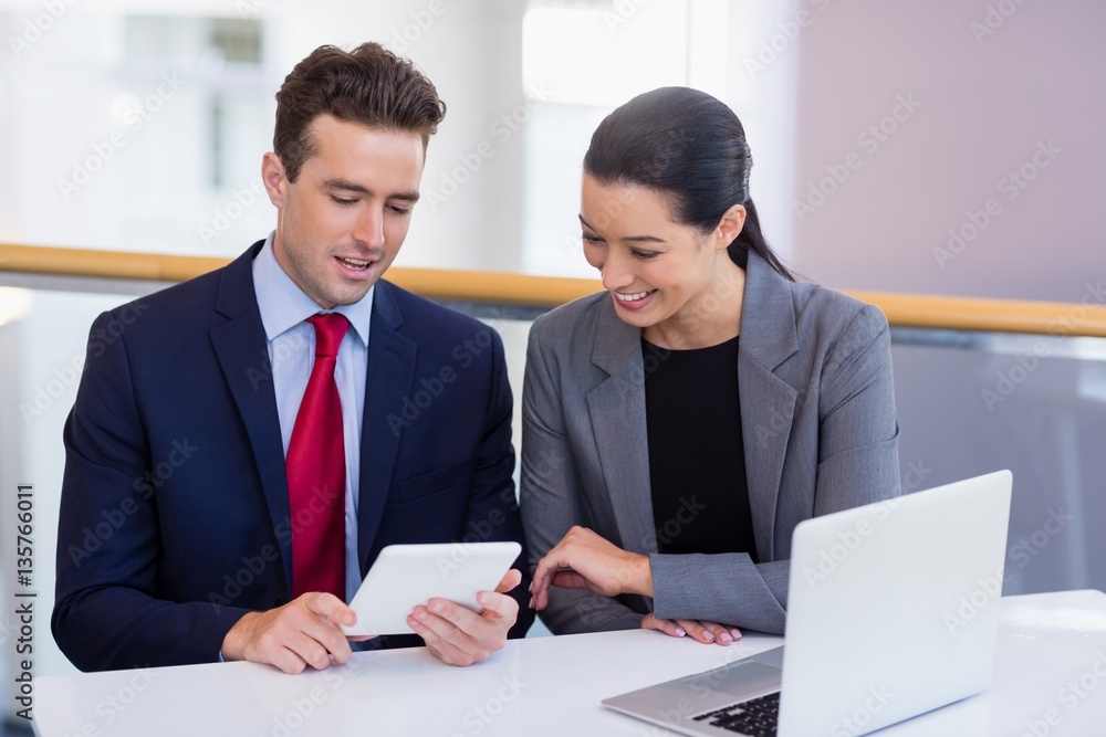 Business executives discussing over digital tablet Business executives discussing over digital tablet