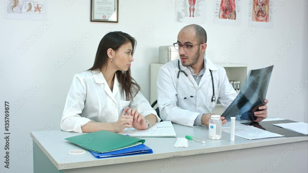Male doctor teaching his unexperienced female trainee how to analyze xray Male doctor teaching his unexperienced female trainee how to analyze xray