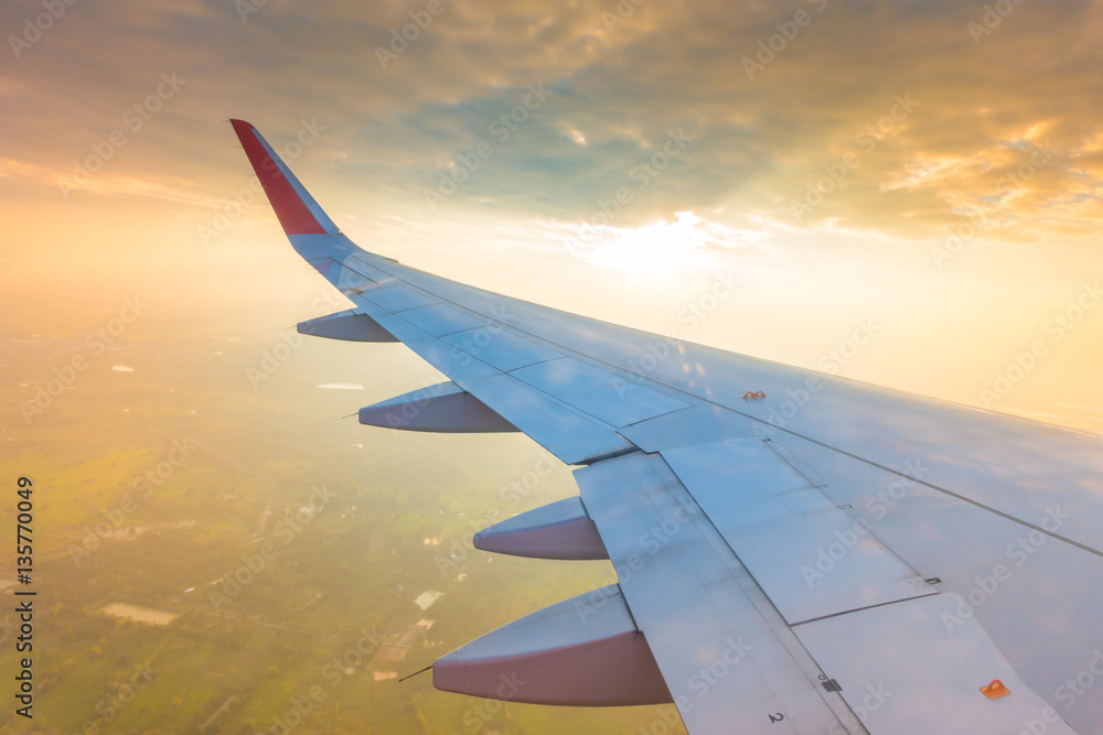Fototapeta premium Wing of an airplane flying above the clouds at sunset . ( Filter