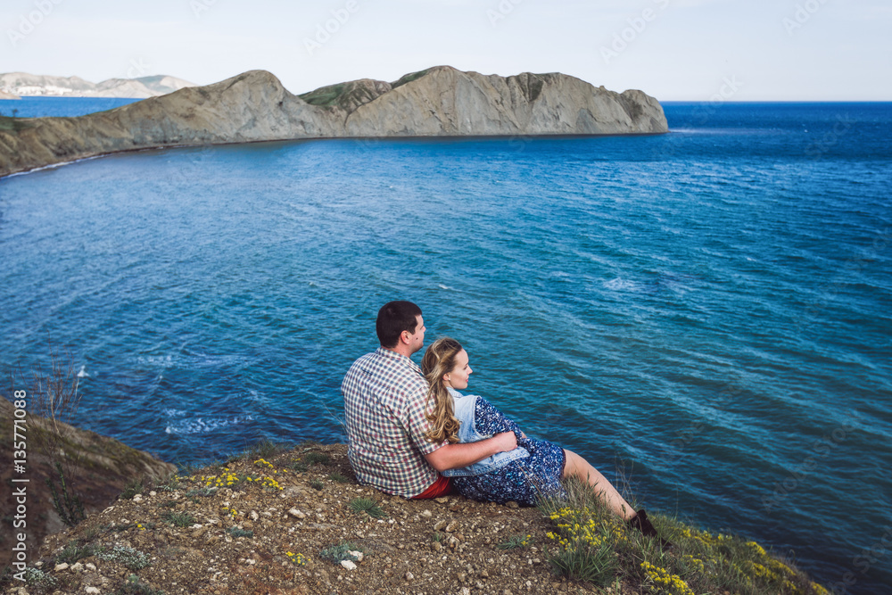 Couple relaxing by the sea with amazing mountain view. Jeans jacket