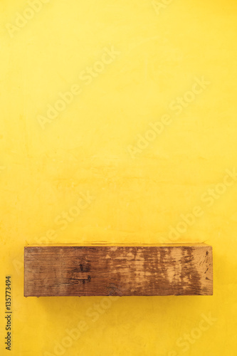 Wooden shelf on yellow wall background
