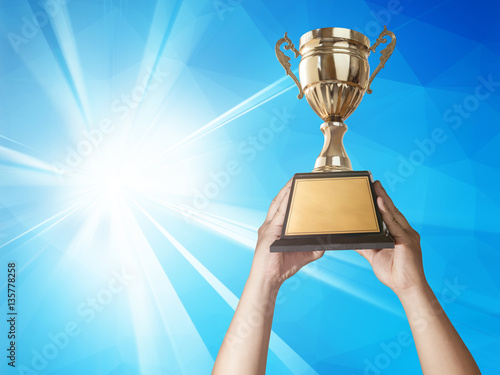 a man holding up a gold trophy cup with abstract blue light and