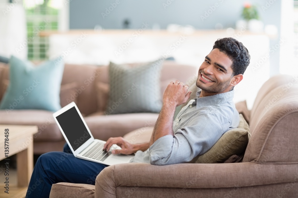 Man sitting on sofa and using laptop in living room at home Man sitting on sofa and using laptop in living room at home