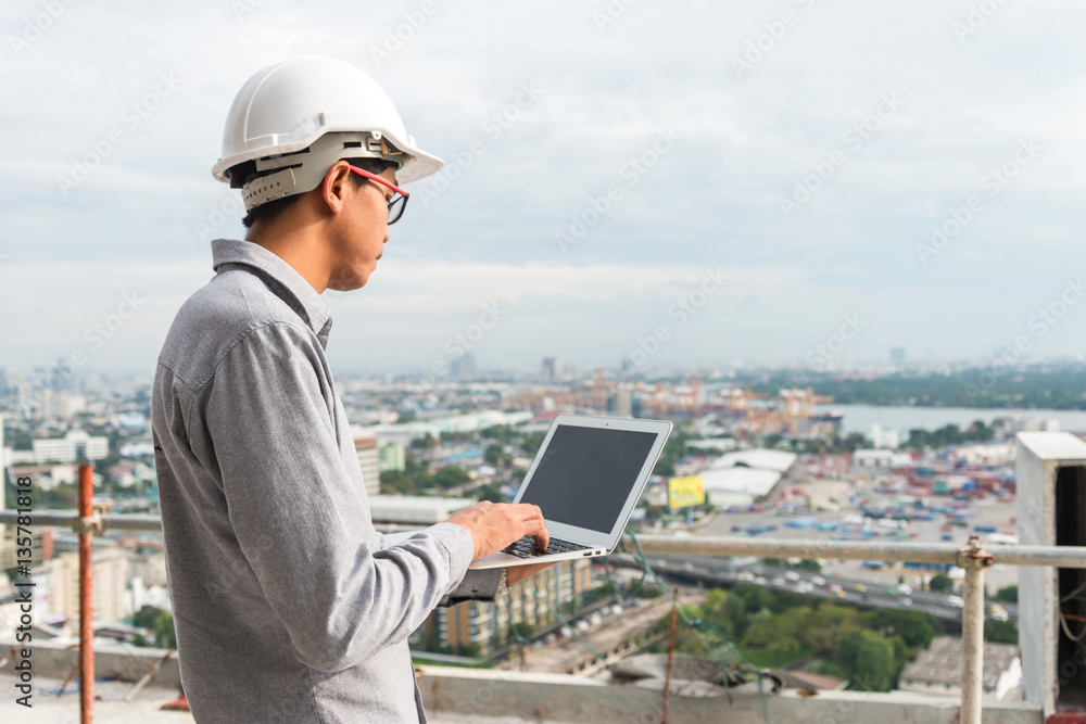 Engineers working on a building site holding a laptop. Engineers working on a building site holding a laptop.