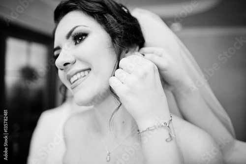 Close up hand of bridesmaid who helped wear earring for bride at