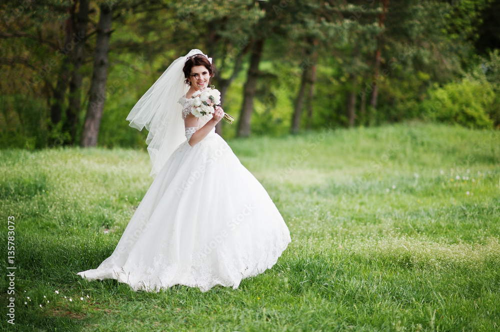 Tenderness brunette bride with wedding bouquet at hand walking o