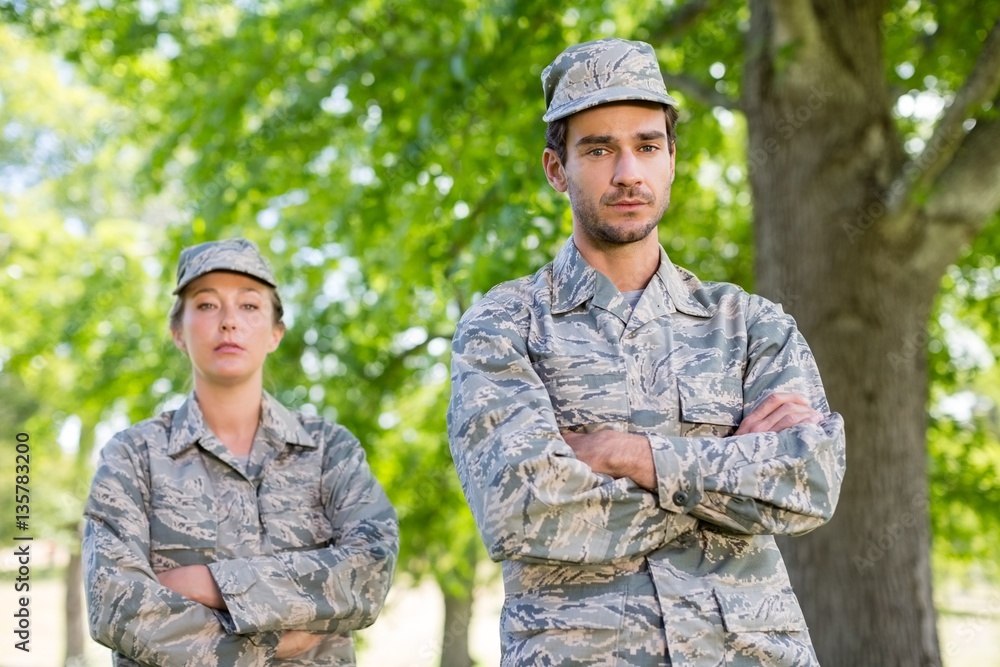 Portrait of a military couple standing with arms crossed in park Portrait of a military couple standing with arms crossed in park