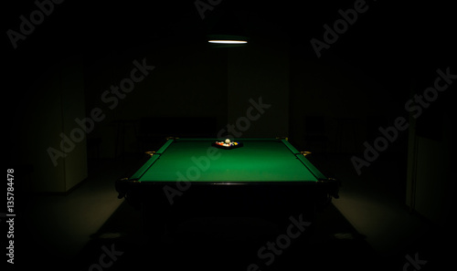 snooker in the dark. billiards in the center under lamp light in the darkness. pills balls and lamp. empty billiard room