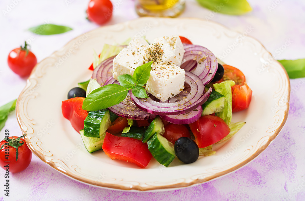 Greek salad with fresh tomato, cucumber, red onion, basil, lettuce, feta cheese, black olives and a Italian herbs on plate. Greek salad with fresh tomato, cucumber, red onion, basil, lettuce, feta cheese, black olives and a Italian herbs on plate.