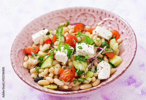 Salad of white beans, tomato, celery, cucumber, arugula, red onion and feta cheese in bowl. Diet food. Healthy lifestyle. Sports nutrition.