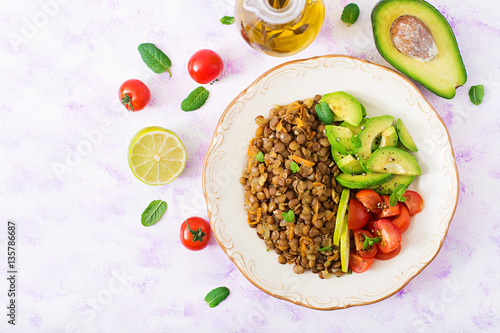 Diet menu. Healthy lifestyle. Lentils porridge and fresh vegetables - tomatoes and avocado on plate. Flat lay. Top view