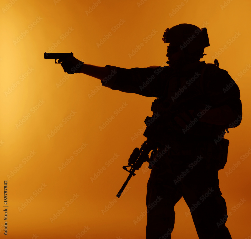 United states Marine Corps special operations command Marsoc raider with weapon aiming pistol. Silhouette of Marine Special Operator orange background United states Marine Corps special operations command Marsoc raider with weapon aiming pistol. Silhouette of Marine Special Operator orange background