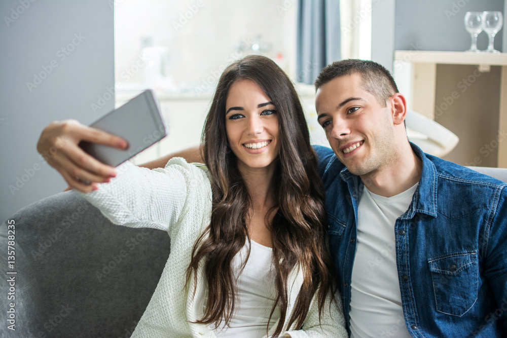 Young couple taking a selfie with smart phone at home. Young couple taking a selfie with smart phone at home.