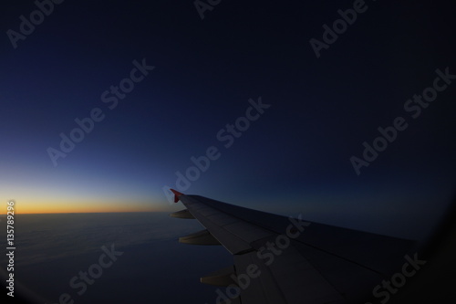 wing of airplane flying on cloud in the afterglow
