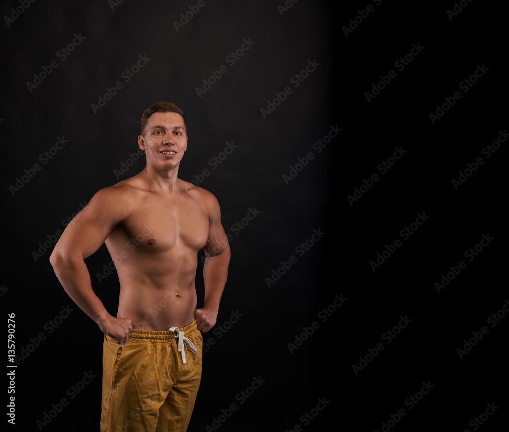 Fototapeta premium Happy smiling bodybuilder stay and look to the camera on dark background with naked body. Trained person shot. Health and sport life concept.