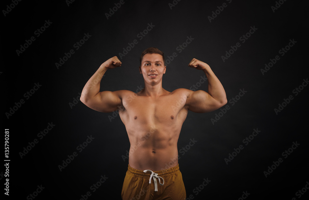 Front view on trained bodybuilder torso. Man show biceps. Portrait of pumped up man on black background. Relief body concept.