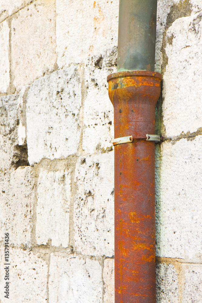 Old cast iron and copper downpipe against a stone wall Old cast iron and copper downpipe against a stone wall