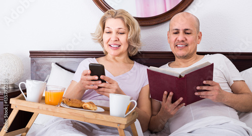 man showing girlfriend something on book during breakfast photo