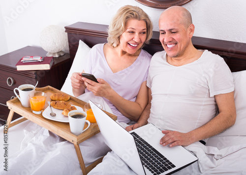 Couple with laptop during breakfast in bed. photo