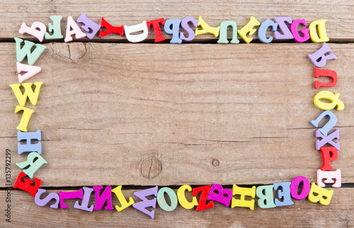 Frame of colored wooden letters on a wooden background