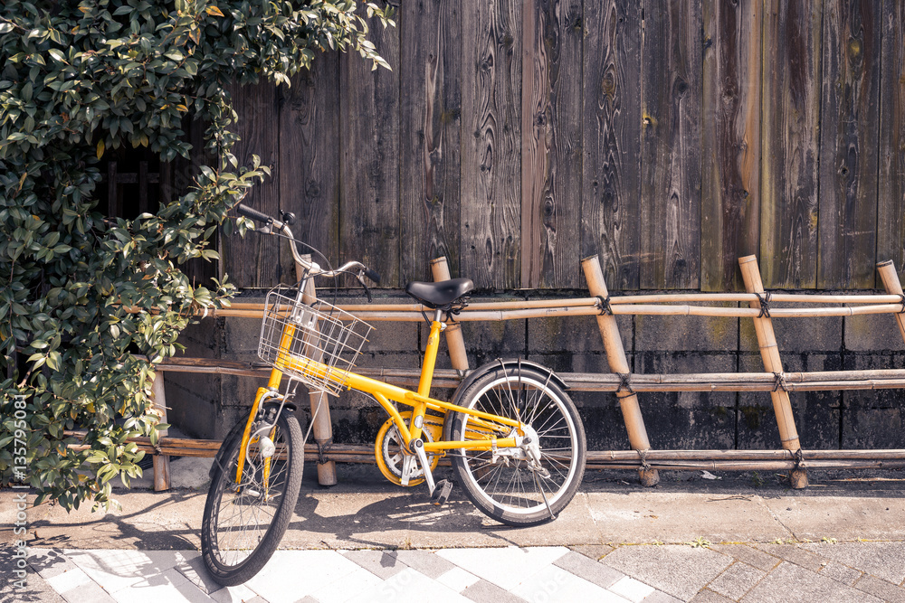 Yellow bicycle on vintage wooden house wall