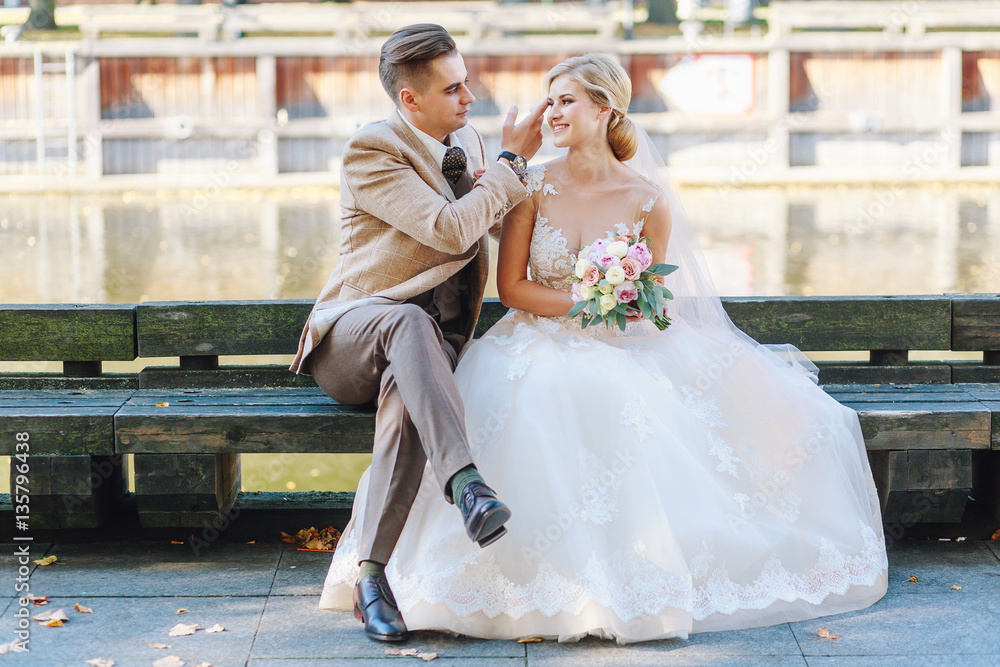 Naklejka premium The bride and groom are sitting on a bench in the city
