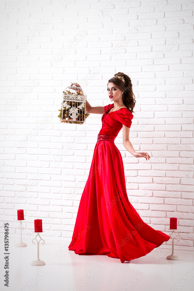 Elegant woman in a long red dress is standing in a white room and holding  cage for birds, dress swirl flashing Stock Photo | Adobe Stock