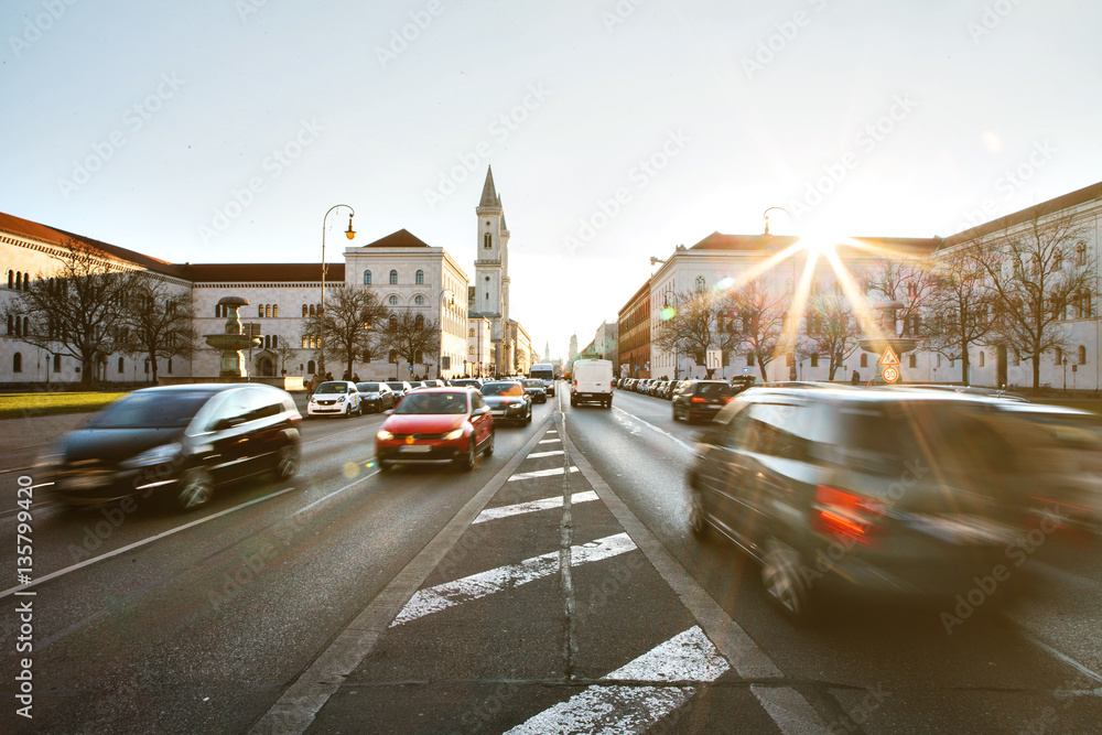 View of the road on the street Leopoldstrasse in Munich - the capital of Bavaria in Germany. Fast blurred motion car on sunset background.