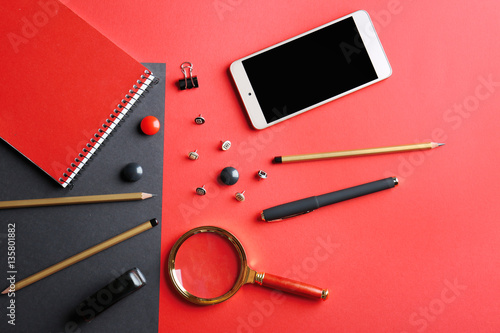 Flat lay of stationery and smart phone on red background