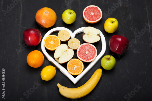 Heart made out of raspberries and blackberries on white background