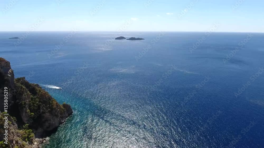Aerial flying over sea near rocky cliff coastline left beautiful coastal landscape with ocean in background and speedboat moving over blue tropical sea amazing place for tourism visit vacation 4k Aerial flying over sea near rocky cliff coastline left beautiful coastal landscape with ocean in background and speedboat moving over blue tropical sea amazing place for tourism visit vacation 4k