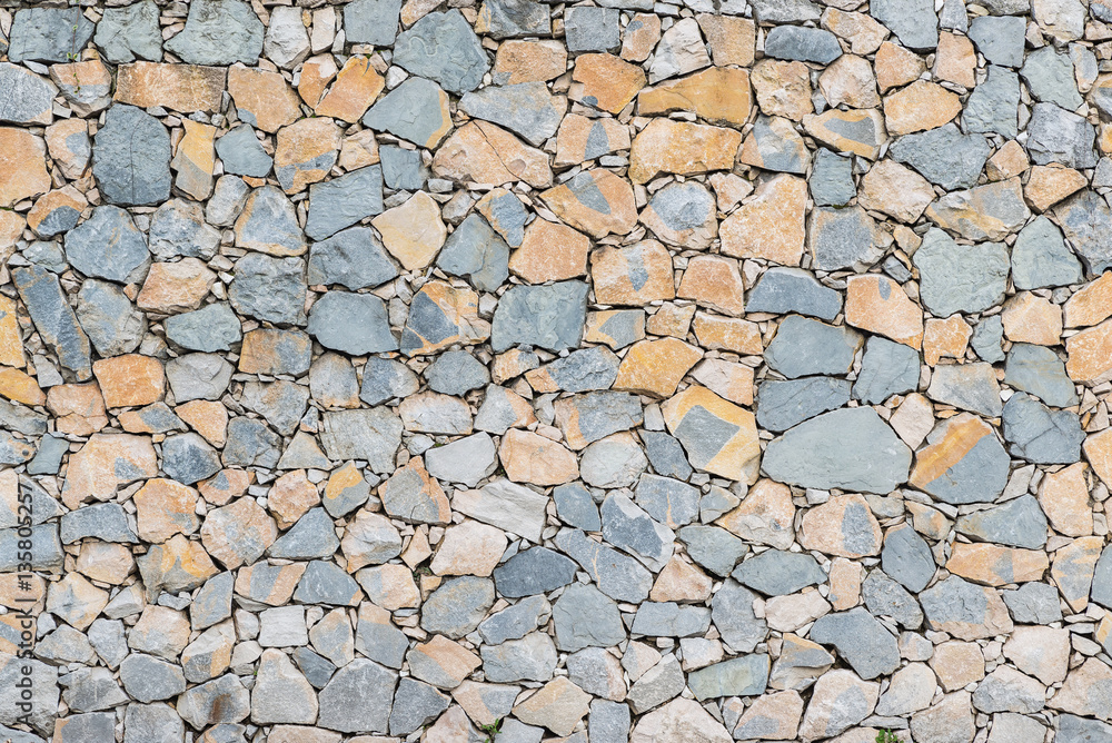 Background stone wall texture. Dry wall with stones arranged irregularly Background stone wall texture. Dry wall with stones arranged irregularly