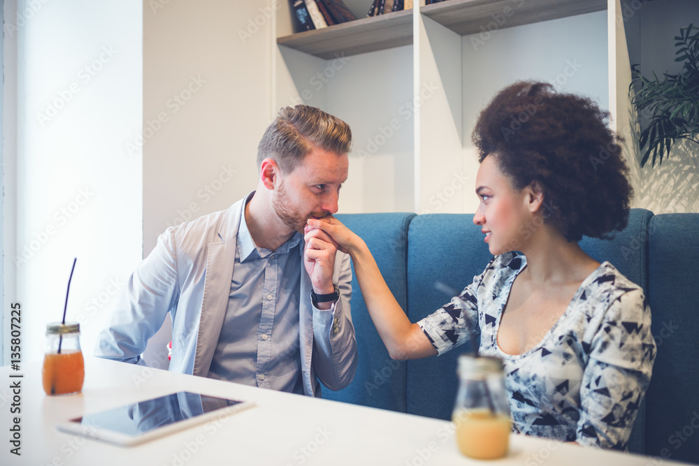 Happy middle age interracial couple sitting in cafe bar. Man giving Valentine's day gift to his girlfriend or wife. Happy middle age interracial couple sitting in cafe bar. Man giving Valentine's day gift to his girlfriend or wife.