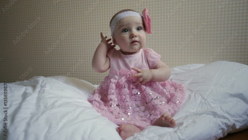 beautiful little girl in a pink dress sitting on a bed beautiful little girl in a pink dress sitting on a bed