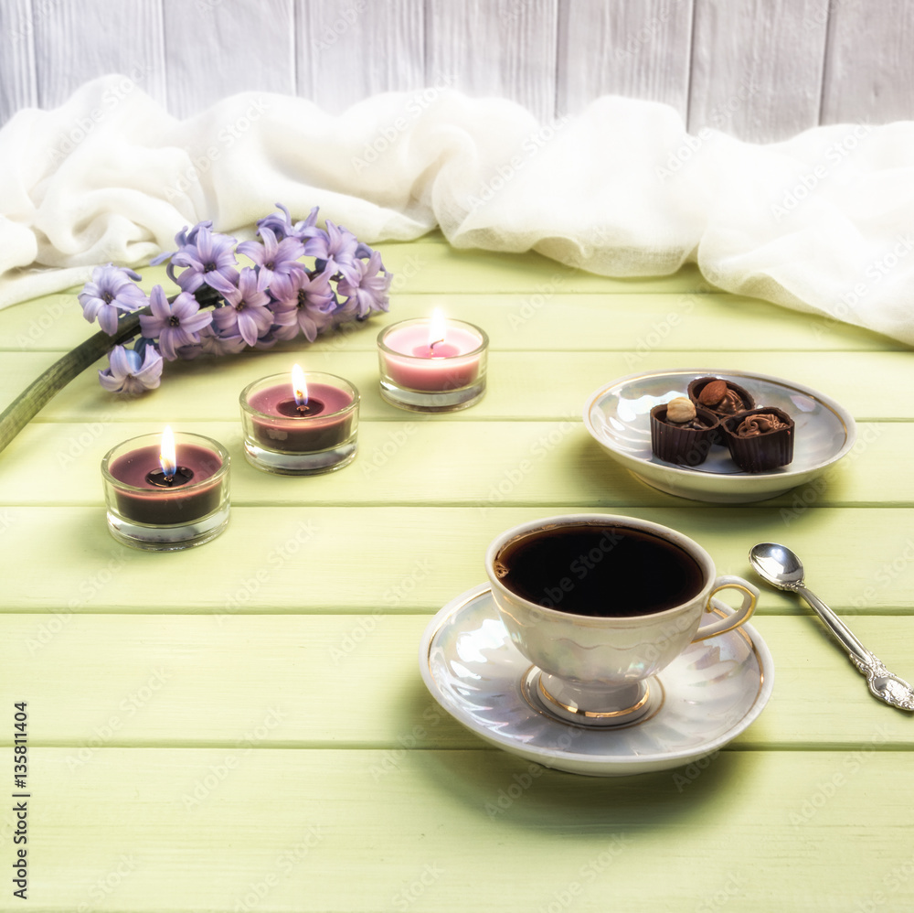 Cup of black coffee, candles and flowers on a wooden background. Cup of black coffee, candles and flowers on a wooden background.