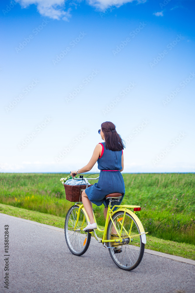 back view of woman riding retro bicycle in countryside back view of woman riding retro bicycle in countryside
