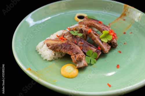 Grilled pork ribs and rice on plate black background.